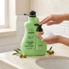 Dłoń naciska pompkę mydła w piance Vione Olive Oil 2000 ml przy umywalce